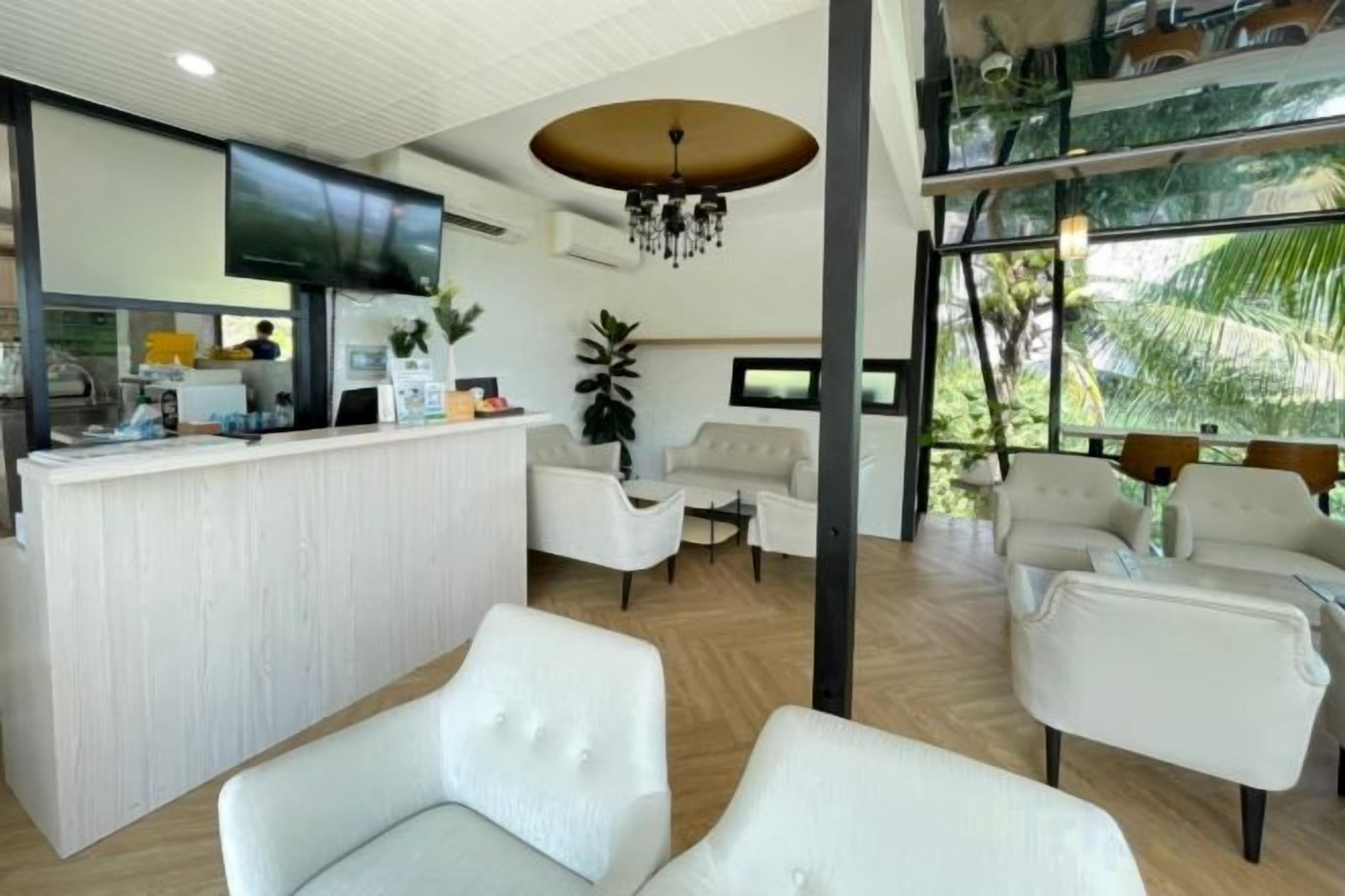 A modern hotel lobby with a reception desk, seating area, and large windows.