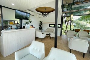 A modern hotel lobby with a reception desk, seating area, and large windows. - Sky Hill Villa Surattthani (Surat Thani)