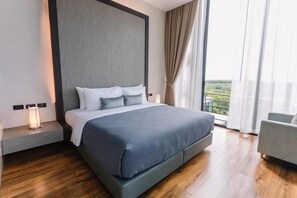 A modern hotel room with a large bed, a bedside table with a lamp, a view of the outdoors, and a balcony. - Sky Hill Villa Surattthani (Surat Thani)
