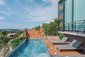 A rooftop pool with lounge chairs, a wooden fence, and a view of the cityscape. - Sky Hill Villa Surattthani (Surat Thani)
