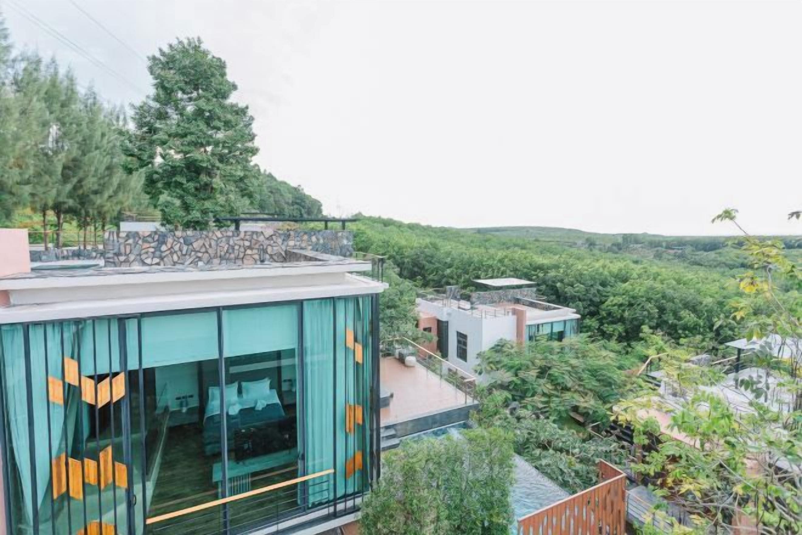 A modern building with large windows and a view of a forested area.