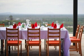A dining table set for six with chairs, a view of the landscape, and a clear sky. - Sky Hill Villa Surattthani (Surat Thani)