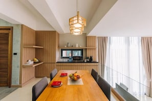 A modern dining area with a wooden table, chairs, and a hanging light fixture. - Sky Hill Villa Surattthani (Surat Thani)