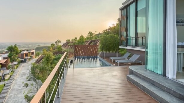 Un hotel moderno con piscina en la azotea, sillones de descanso y vistas a la ciudad.