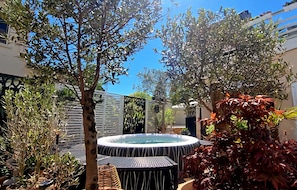 A hot tub surrounded by plants and a wooden fence.