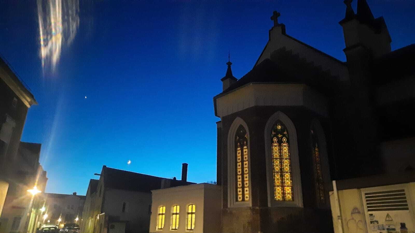 Una chiesa con vetrate illuminate al crepuscolo.