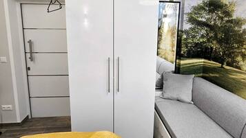 Ein Zimmer mit einem weißen Kleiderschrank, einem grauen Sofa und einer gelben Decke.