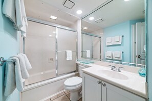 A modern bathroom with a glass shower enclosure, white toilet, and a sink with a glass soap dish. - Summer House 905A | Gulf Front | Resort Amenities | My Beach Getaways (Orange Beach)