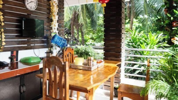 Une table à manger en bois, des chaises, une horloge et un téléviseur accroché au mur.