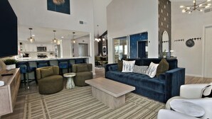 A spacious living area with a dark blue sofa, a coffee table, and a kitchen in the background. - Lunar: Old Town Luxury• Heated Pool• 2 Kings• Gameroom• Hottub• Karaoke• Privacy (Scottsdale)