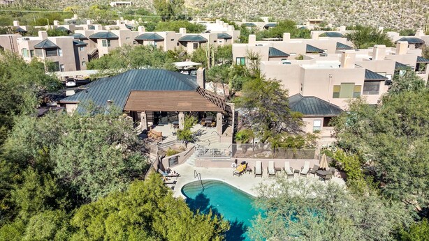An aerial view of a resort with multiple buildings, a swimming pool, and surrounding greenery.