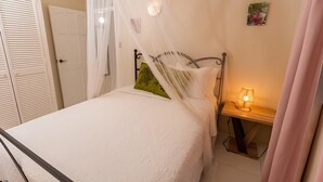 A neatly made bed with a white bedspread and a green pillow, a bedside table with a lamp, and a door with louvered shutters. - Providence,where nature meets home, every path leads to peace.
Strong WIFI, AC. (Mahaut)