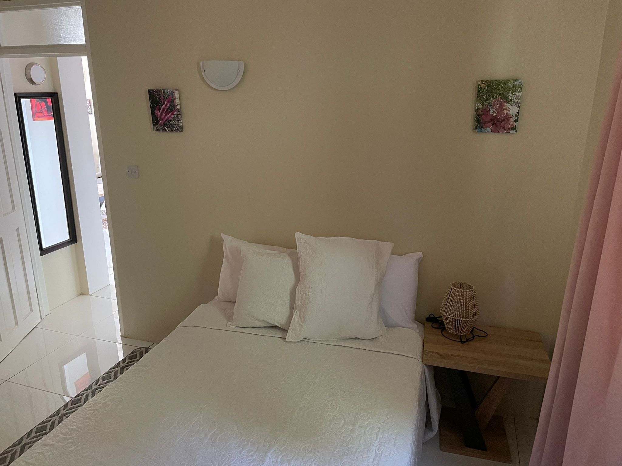 Un dormitorio con una cama, almohadas, una mesita de noche y dos obras de arte colgadas en la pared.