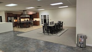 A spacious kitchen with dark wooden cabinets, a central island with stools, and a dining area with a large table and chairs. - Spacious House Ideal for Sports Teams, Across from Spooky Nook in Manheim, PA (Manheim)