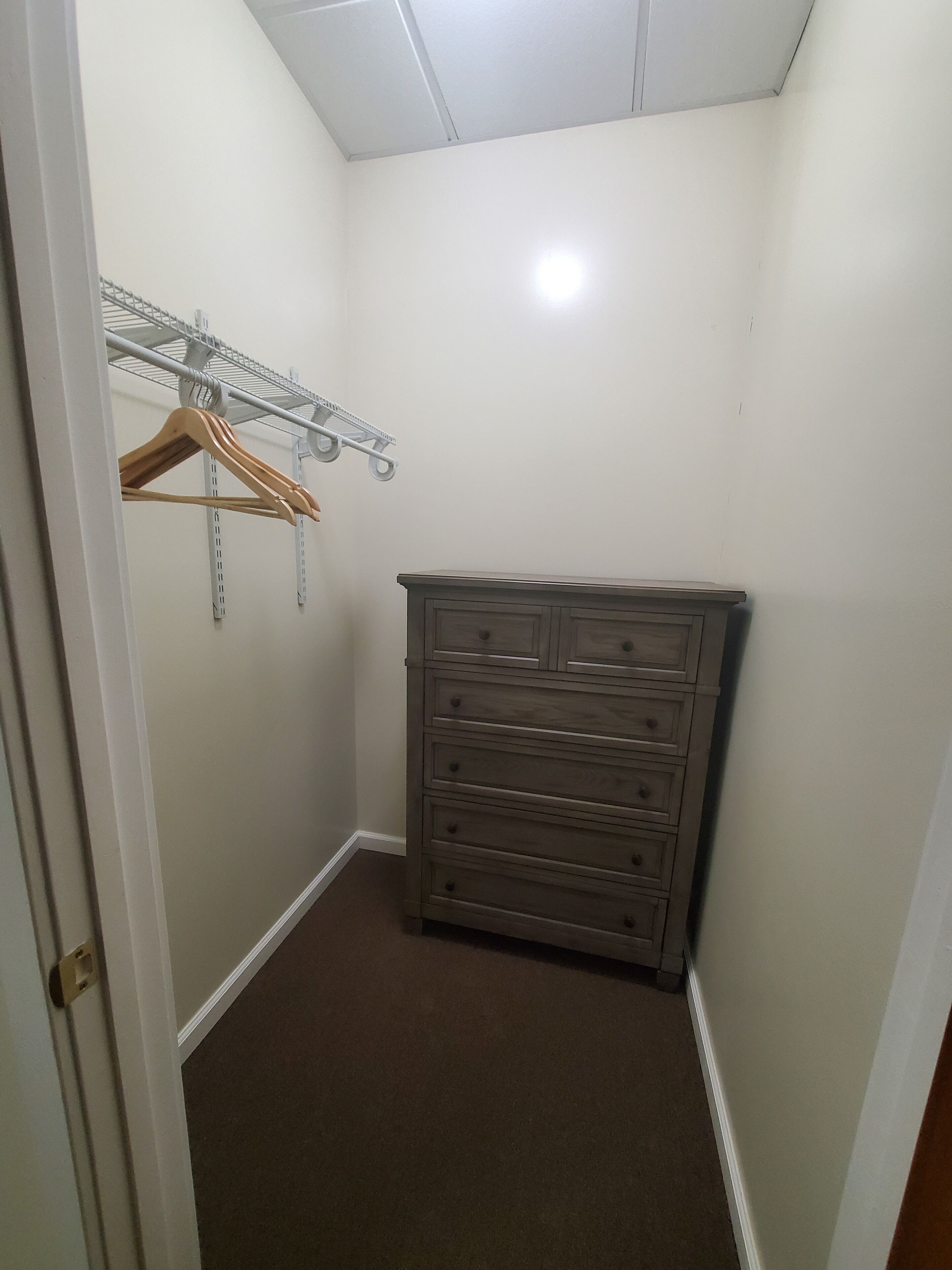 Een kleine, zwak verlichte kast met een houten dressoir en een metalen rek.