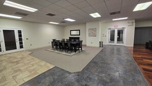 A conference room with a table and chairs, carpeted flooring, and a ceiling with fluorescent lights. - Spacious House Ideal for Sports Teams, Across from Spooky Nook in Manheim, PA (Manheim)