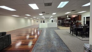 A spacious hallway with a wooden floor, a kitchen area with dark wooden cabinets, and a seating area with a table and chairs. - Spacious House Ideal for Sports Teams, Across from Spooky Nook in Manheim, PA (Manheim)