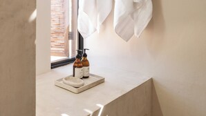 A bathroom with a marble countertop, a window with blinds, and two bottles of lotion. - Ola de Luna, Charming bungalow in El Pescadero with AC, Pool and yoga deck. (El Pescadero)