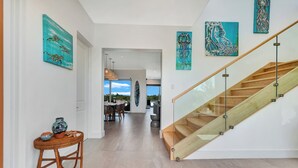Ein modernes Interieur mit einer Holztreppe, einem Essbereich und Kunstwerken an den Wänden.