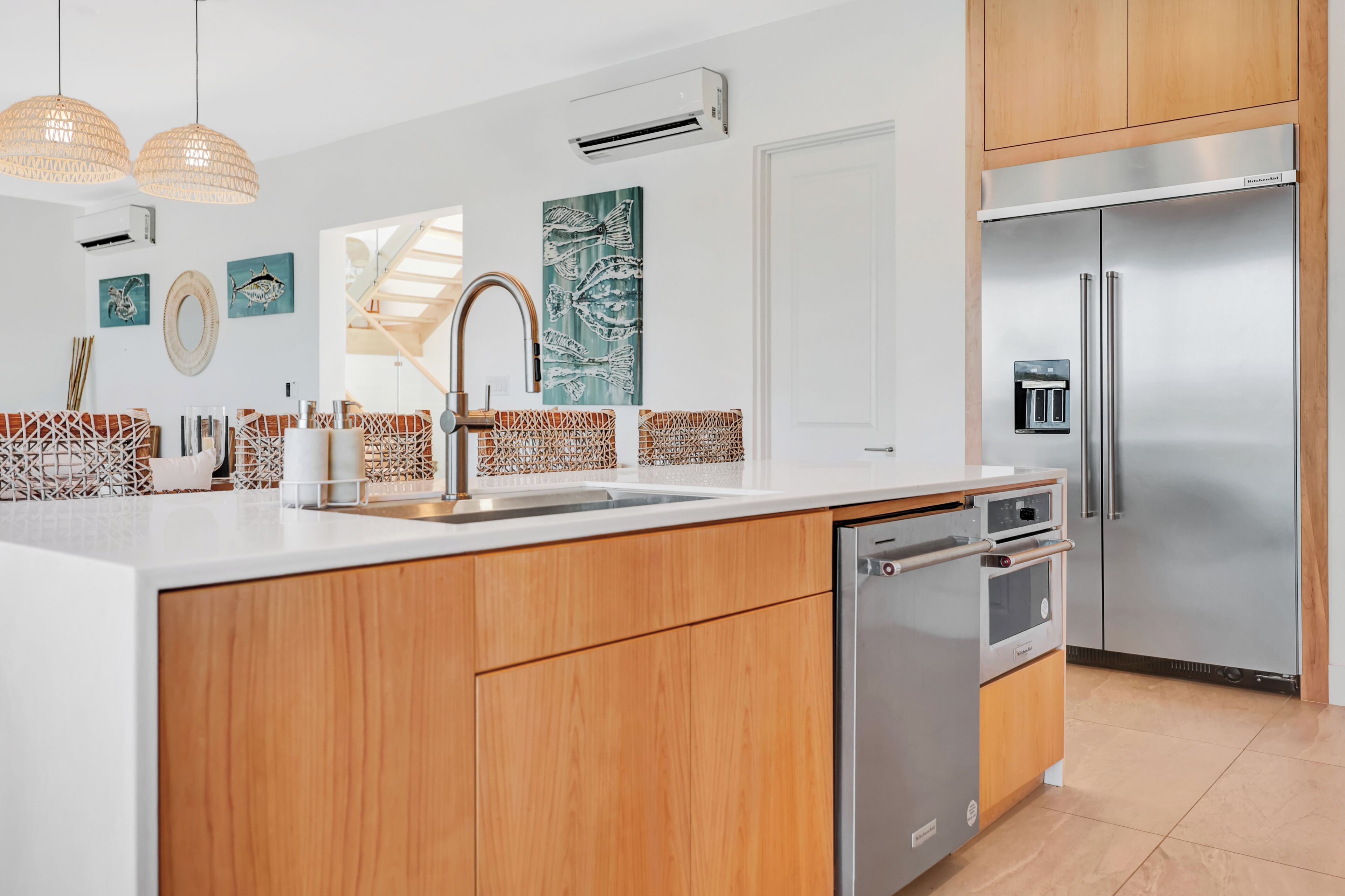 Una cucina moderna con mobili in legno, un frigorifero in acciaio inossidabile, una lavastoviglie e un lavello con pannello decorativo.