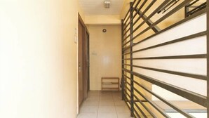 A narrow hallway with a metal gate, a door, and a bench. - RedDoorz @ Moss Hotel Guevarra Dasmarinas (Dasmarinas)