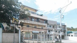 A multi-story building with a gated entrance, a staircase leading to the upper floors, and a sign indicating a business or commercial use. - RedDoorz @ Moss Hotel Guevarra Dasmarinas (Dasmarinas)