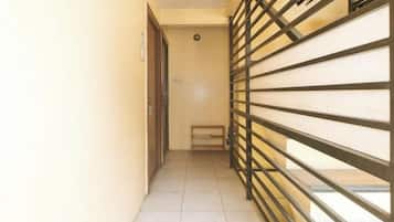 A narrow hallway with a metal gate, a door, and a bench.