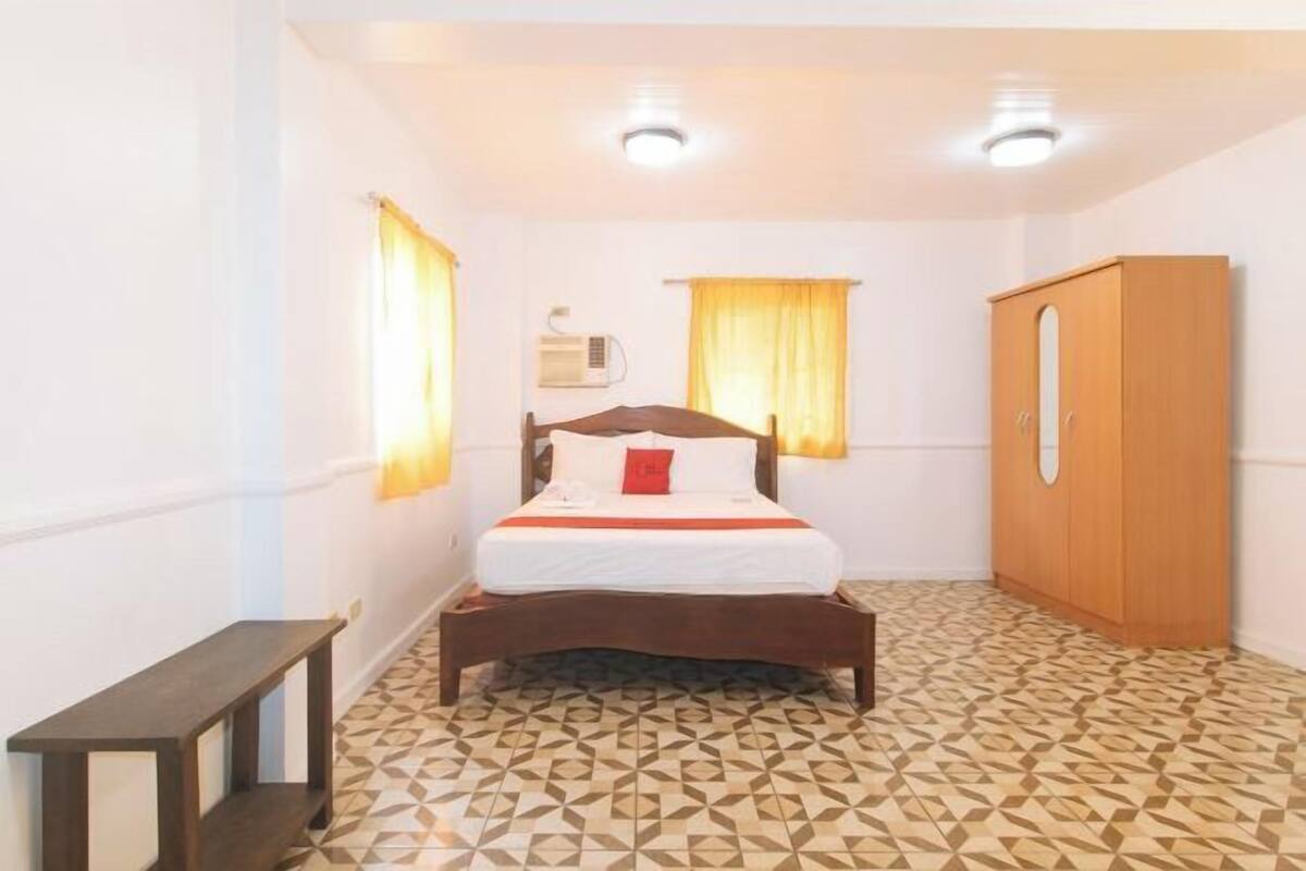 Un dormitorio con cama, armario, mesita de noche y un calentador de pared.