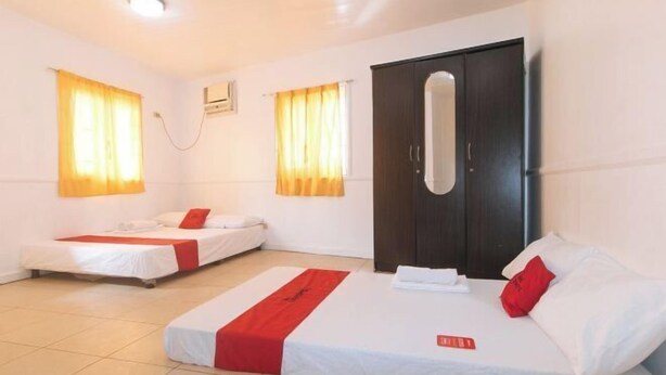 A hotel room with two single beds, a large wardrobe, and a small window. - RedDoorz @ Moss Hotel Guevarra Dasmarinas (Dasmarinas)