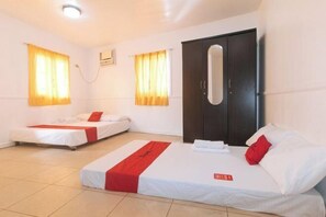 Habitación de hotel con dos camas individuales, un armario grande y una ventana pequeña.