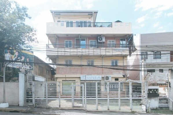 A multi-story building with a gated entrance, balconies, and a sign indicating a business or service. - RedDoorz @ Moss Hotel Guevarra Dasmarinas (Dasmarinas)