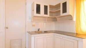A kitchen with white cabinets, a sink, and a window with blinds. - RedDoorz @ Moss Hotel Guevarra Dasmarinas (Dasmarinas)
