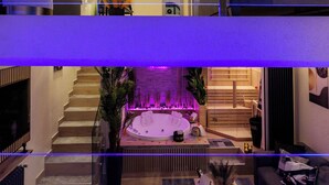 Een moderne hotellobby met een centrale jacuzzi, een trap en een zithoek.