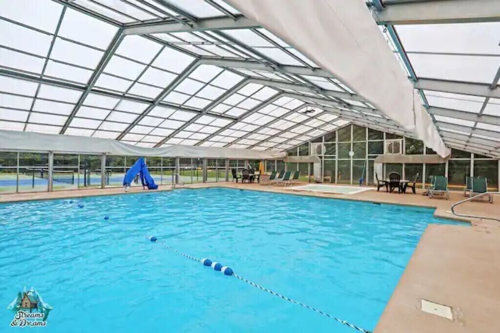 Indendørs swimmingpool med glasloft, liggestole og en stor, blå 'A'-dekoration.
