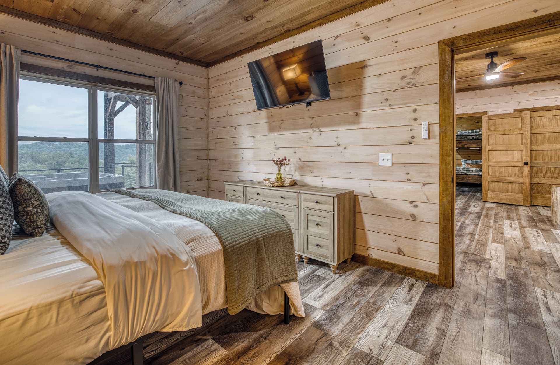 Un intérieur en bois comprenant un lit, une commode et un téléviseur fixé au mur.