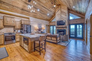 Une cuisine spacieuse avec des meubles en bois, un grand îlot central et une cheminée intégrée.