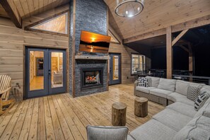 A cozy interior with a fireplace, wooden flooring, and a large sofa. - New Luxury Cabin in Coosawattee River Resort _ Hot Tub + Views + Sleeps 12 (Ellijay)