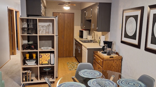 Une cuisine compacte avec un coin repas, des meubles en bois et un ventilateur de plafond.