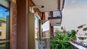 A balcony with a glass door, a metal railing, and a potted plant.