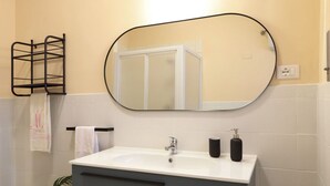 A bathroom with a white sink, a mirror, a towel rack, and a potted plant.