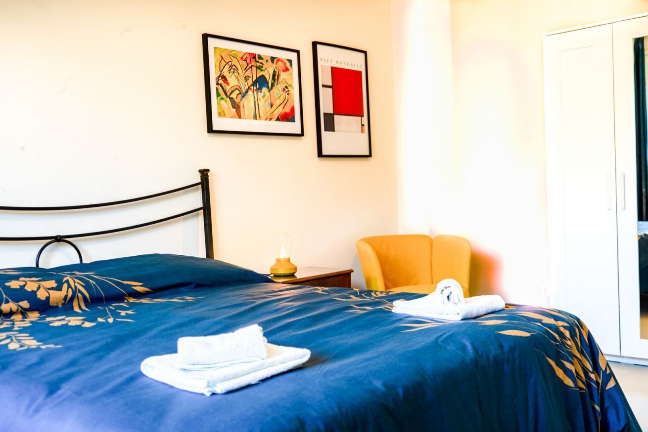 Ein Hotelzimmer mit einem Bett, einem Sessel und zwei gerahmten Kunstwerken an der Wand.