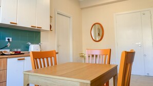 A compact kitchen with white cabinets, a wooden table, and two orange chairs.