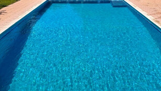 A rectangular swimming pool with clear blue water and a tiled edge. - Versace-Style Villa with Outdoor Spaces and Pool (Borgo Podgora)