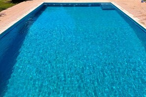 Ein rechteckiger Pool mit klarem, blauem Wasser und einer gefliesten Kante.