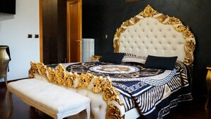 A bedroom with a large bed, a bench, a door, and a framed picture on the wall. - Versace-Style Villa with Outdoor Spaces and Pool (Borgo Podgora)