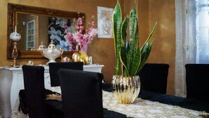 A dining area with a table set for four, a decorative plant in a gold vase, and a mirror on the wall. - Versace-Style Villa with Outdoor Spaces and Pool (Borgo Podgora)