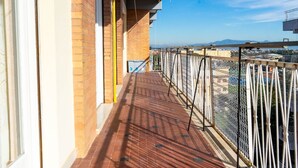 Un balcon donnant sur un paysage urbain, avec un mur de briques et une rambarde en métal.