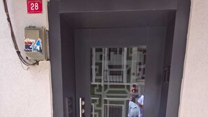 A door with a numeric sign, a glass panel with a geometric pattern, and a person standing outside.