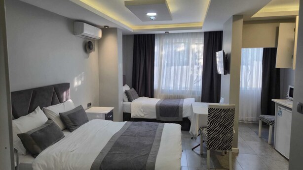 A hotel room with two beds, a desk, a chair, and a TV.