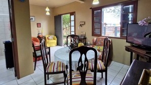 A dining area with a round table, chairs, and a television.